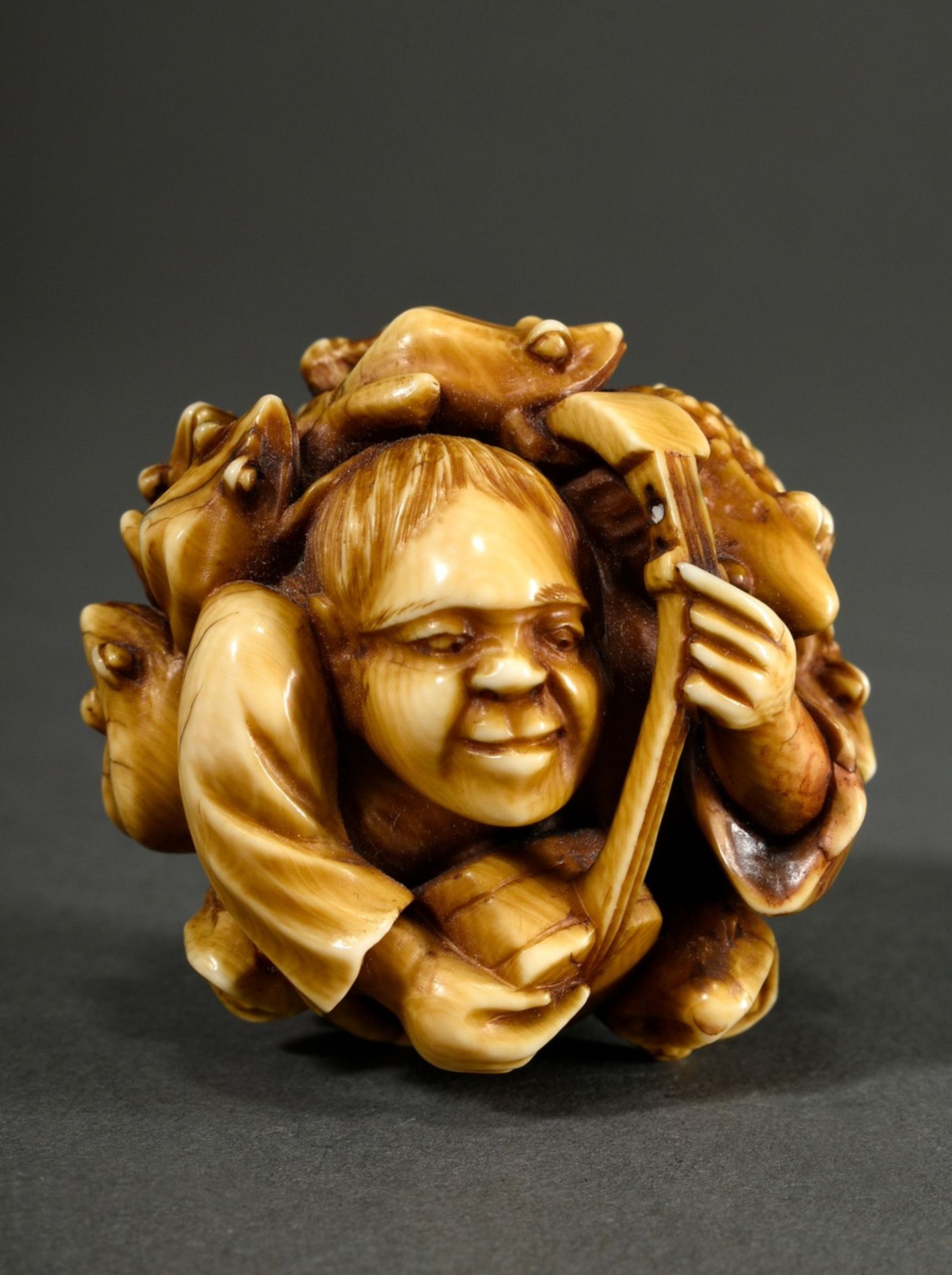 Ivory okimono in ball shape ‘Shamisen player with toads’, patinated, Japan Meiji period, around 190