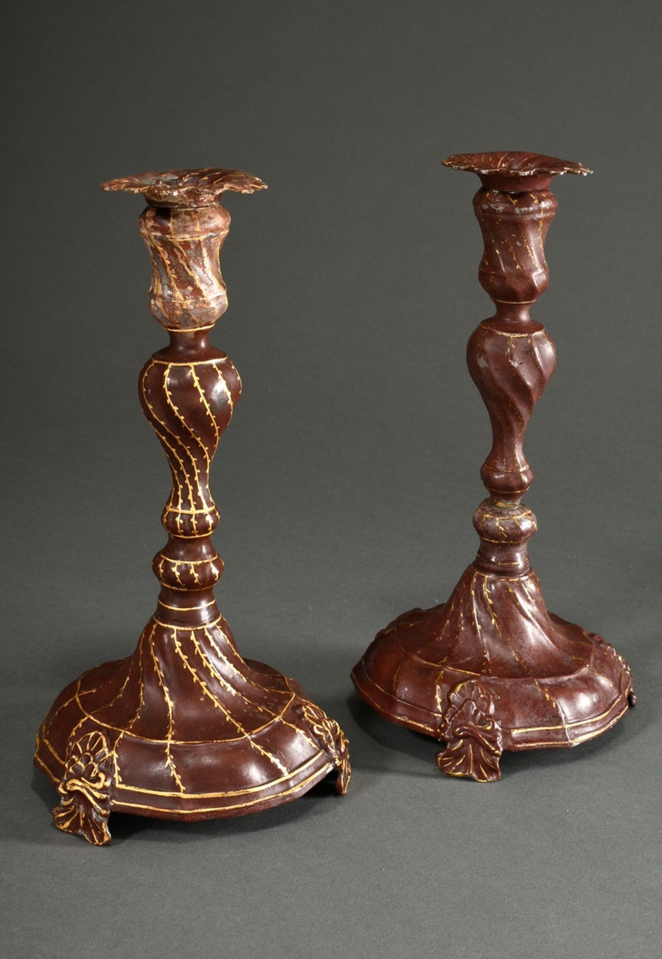 A pair of baroque pewter candlesticks with twisted features on a baluster shaft and bell foot over 