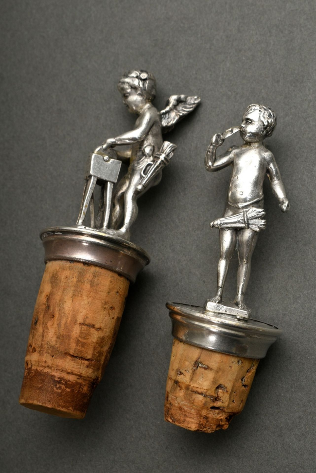 2 Various bottle corks, silver-plated metal, approx. 1900: cupids with grindstone and theatre mask,