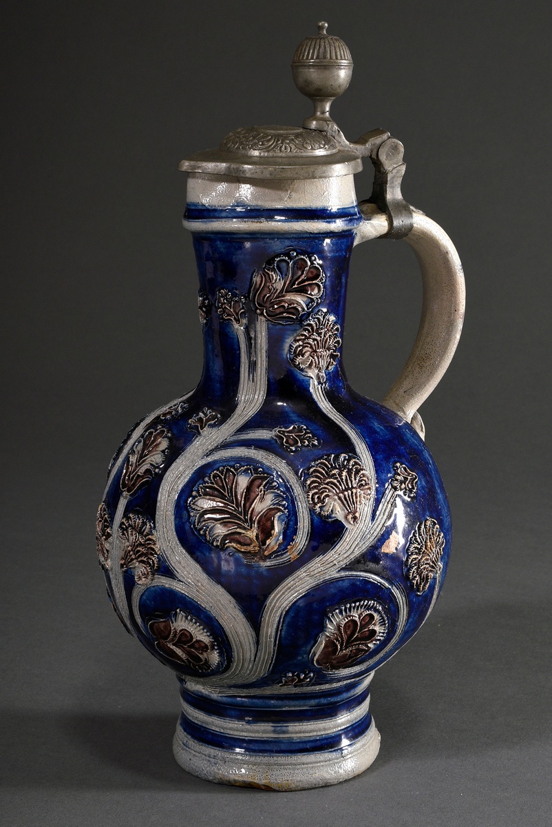 A baluster-shaped Westerwald tankard with semi-plastic floral ornaments and a wide strap handle cur