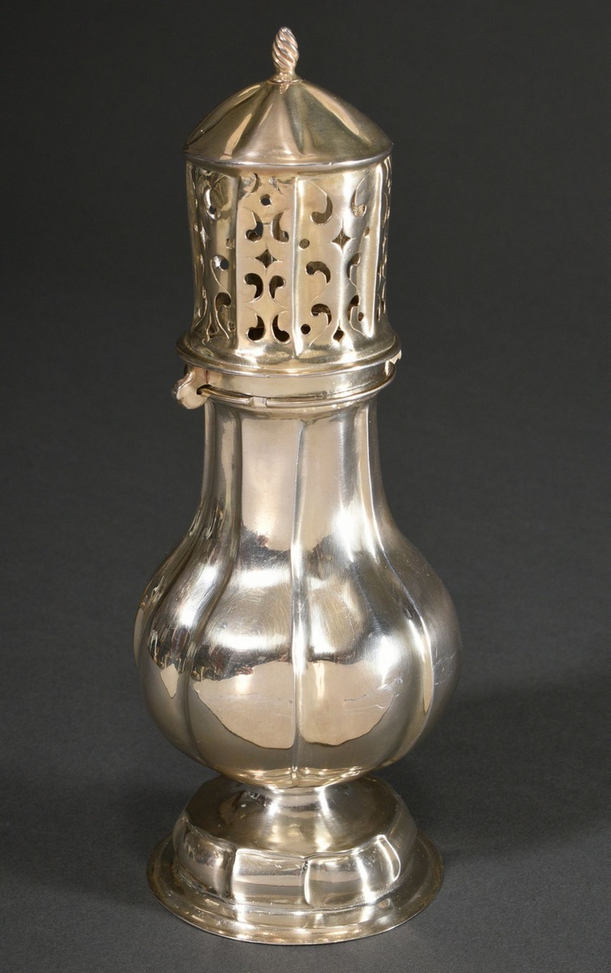 Baroque sugar shaker in baluster form with straight lines on a domed foot, cylindrical lid with orn