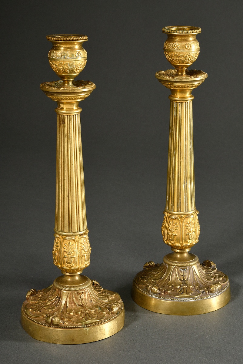 A pair of fine gilt bronze candlesticks with sculpted leaf cuffs and friezes and a brass shaft over