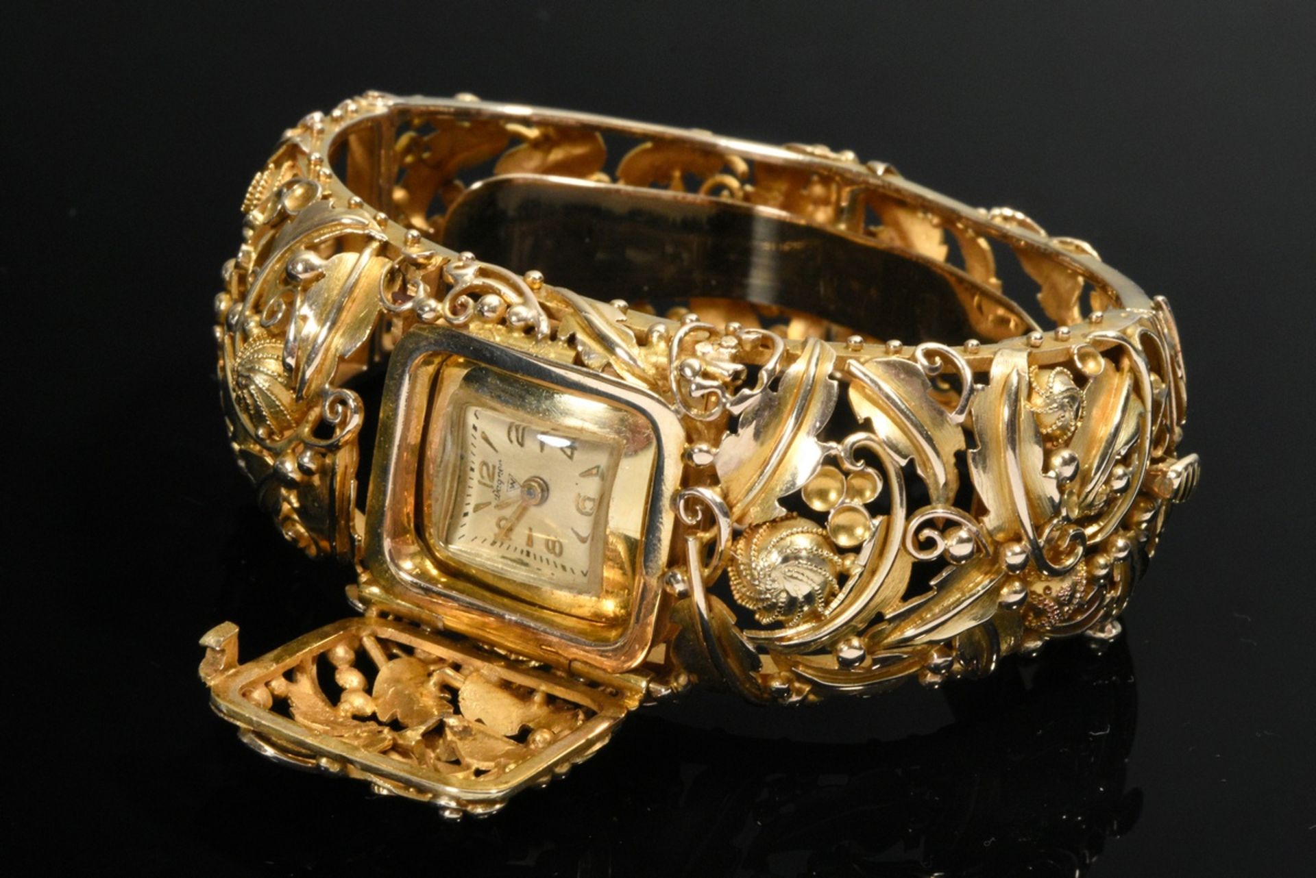 Oval yellow gold 585 bangle with hidden Wagner watch under hinged cover, leaf and flower ornaments 