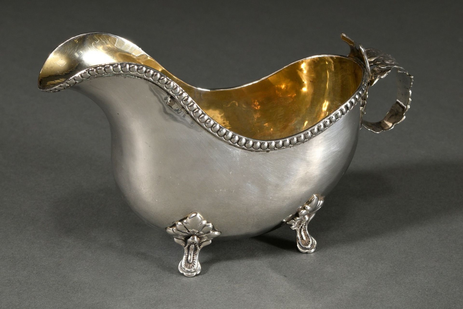 Small butter sauce boat with martelised body on 4 feet with beaded rim and leaf handle, Sweden, 1st