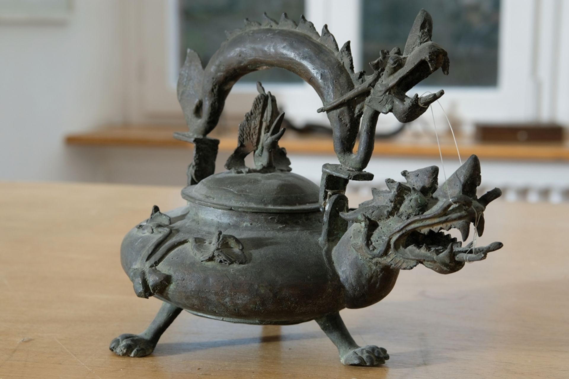 Dragon-shaped tea kettle with tripod stand. 