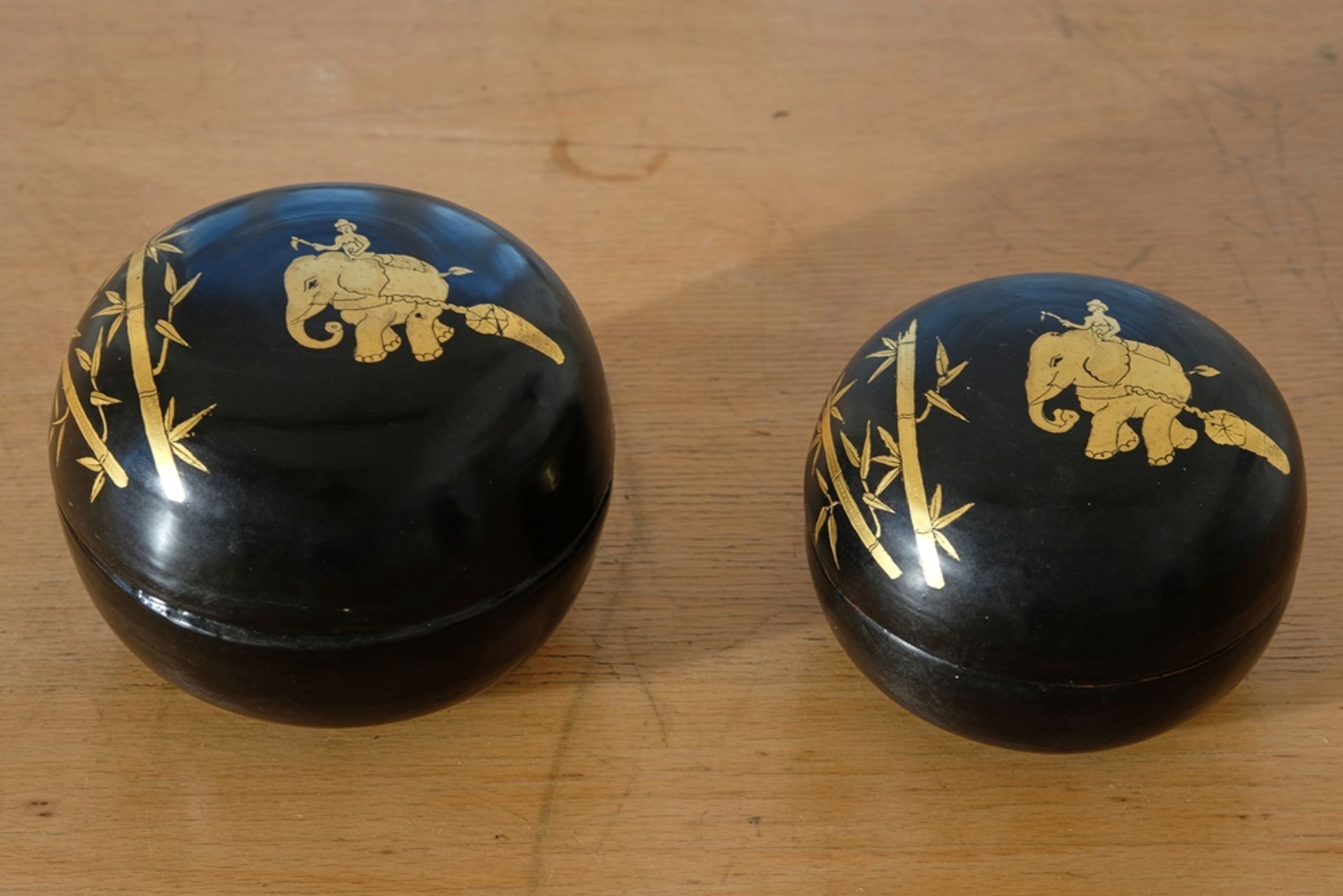 Two lacquer boxes, Burma, 1980s. Black lacquer with gold decoration. Depiction of working elephants