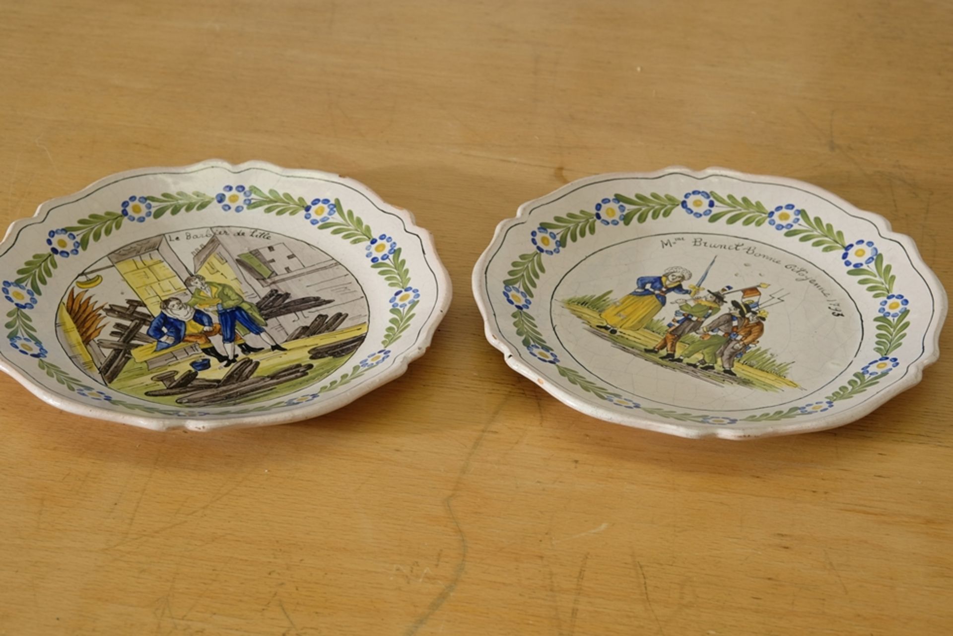 Two antique clay plates, curved shape, painted in the centre, floral decoration on the rim.