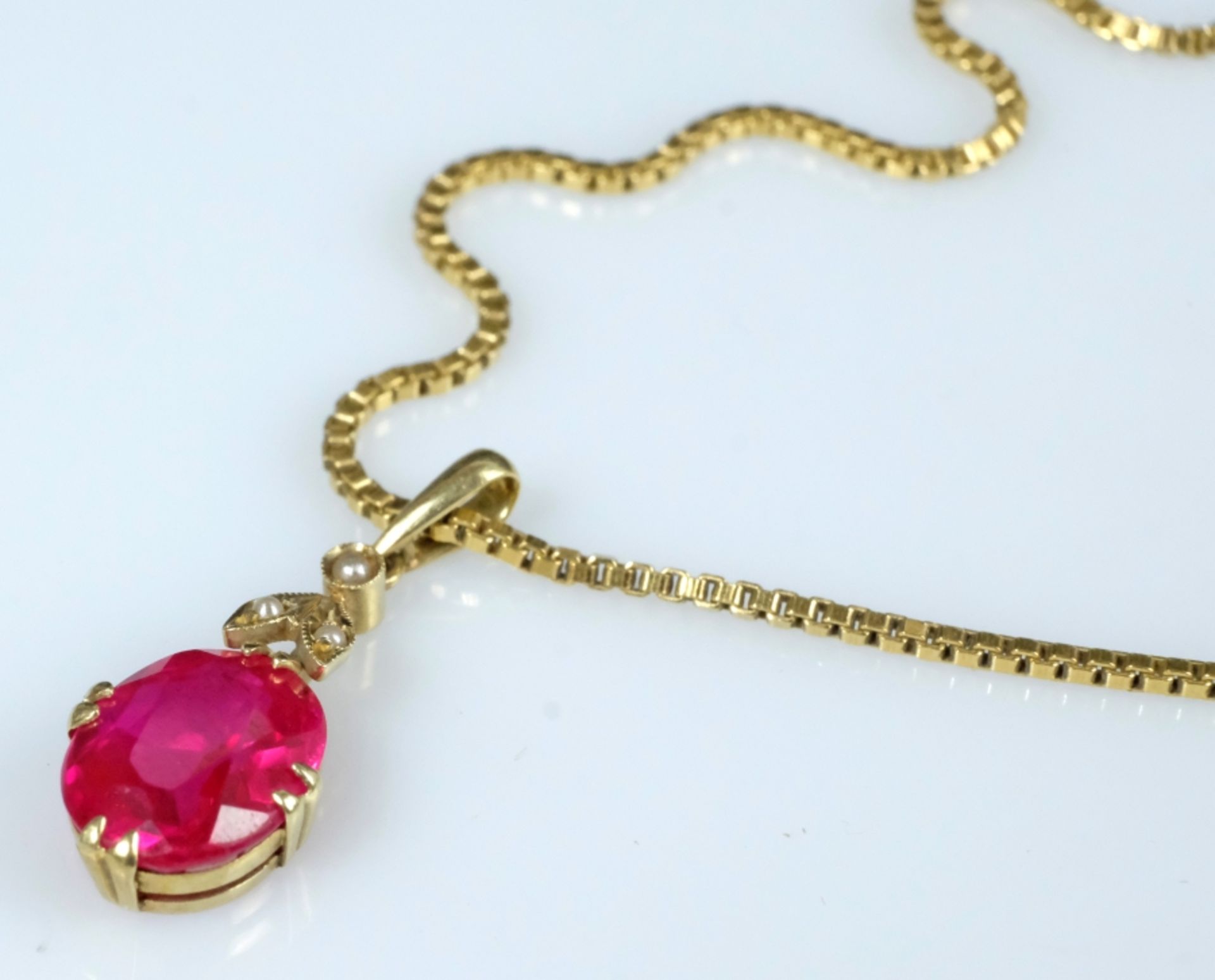 Ruby pendant on a fine gold chain, ruby set in eight fine prongs, setting with three small pearls. 