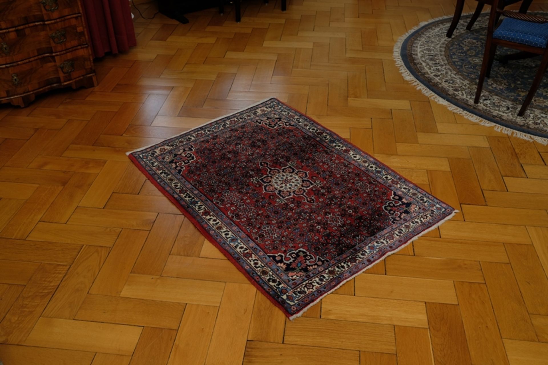 Rug in red and blue tones, rosette in the centre, fringes