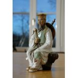 Warrior figure, Chinese. Ceramic. Sitting warrior, carrying sword and shield on his back, holding a