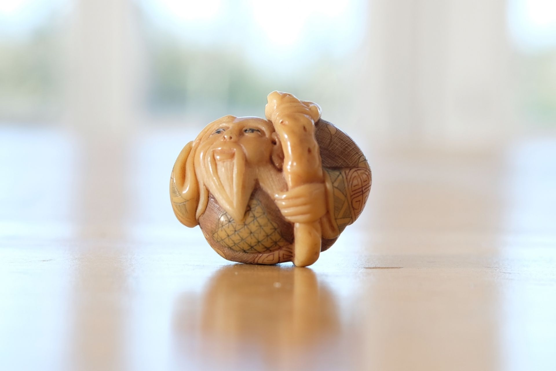 Netsuke, Figur eines alten Mannes mit Bart und Gehstock, signiert unten am Fuß, Höhe 3,5 cm.