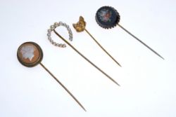 Vier Anstecknadeln mit verschiedenen Motiven: Perlen-Hufeisen, Wolf, Blumen-Mosaik, Camée, jeweils 