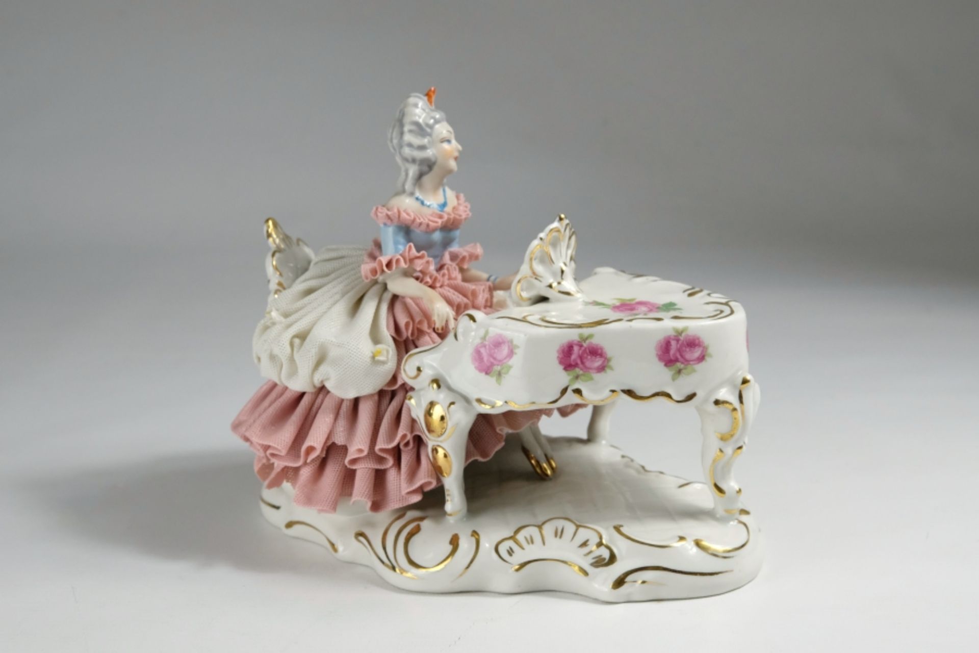 Porcelain figure, lady with a sweeping tulle dress on a wing, painted with roses. 