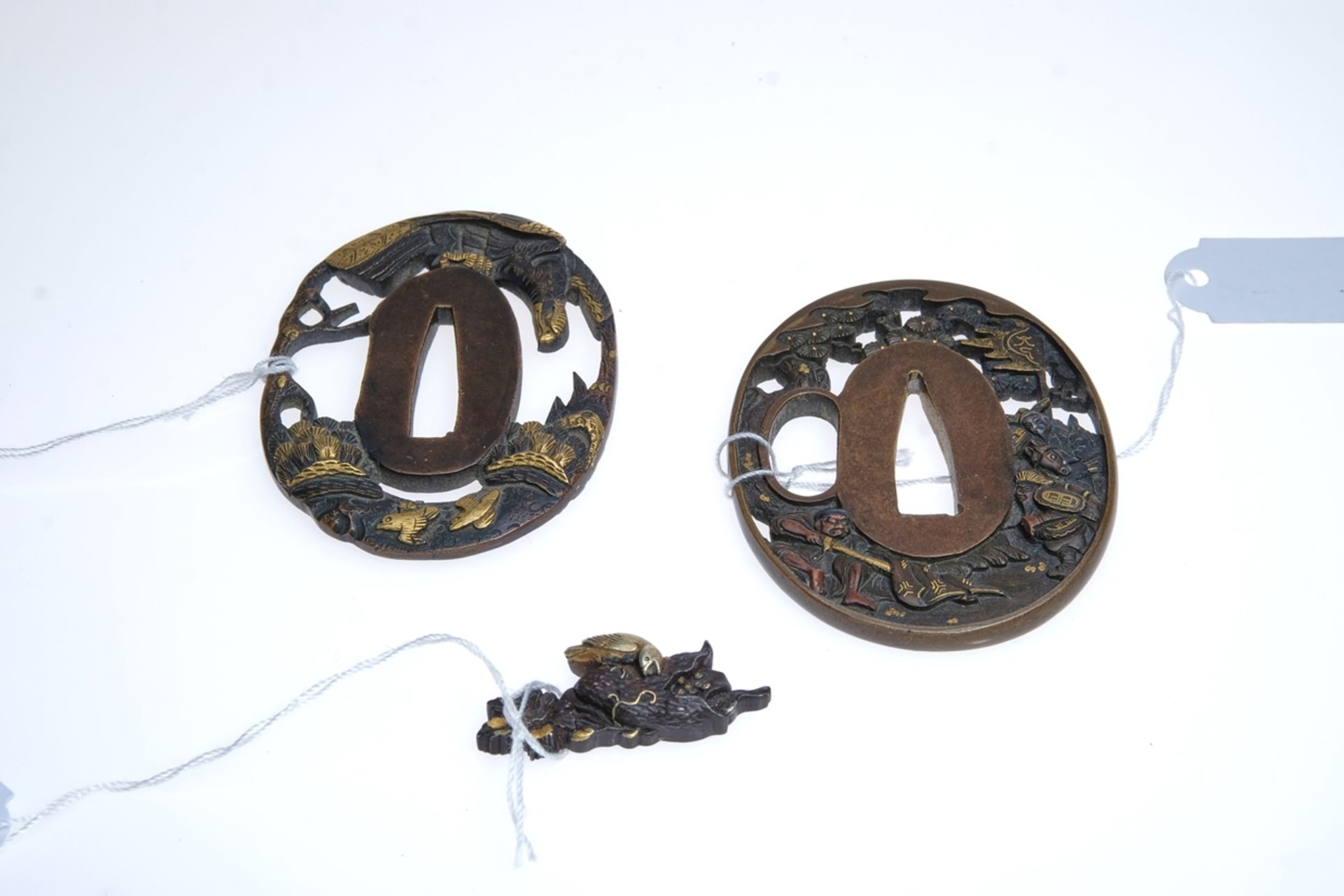 Menuki and two tsubas. One richly decorated with an eagle and other birds, the other with a depicti