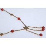 Gold chain with stars and red pearls. The chain forms a larger star, from which three further small