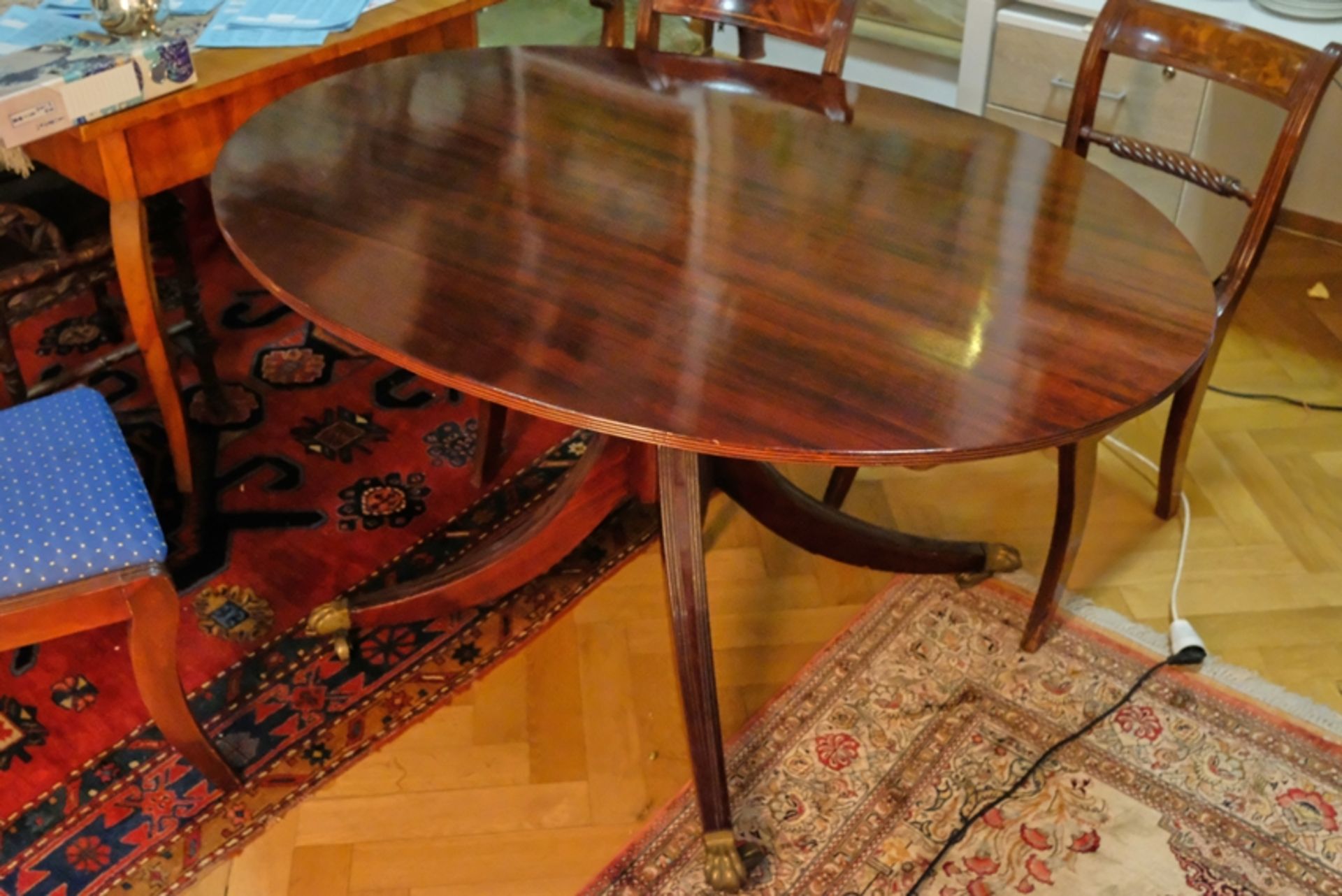 Dining table oval shape, mahogany, on four rollable brass paw feet, 20th century.