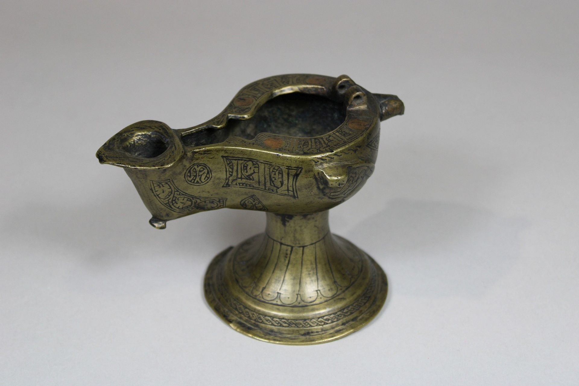 Öllampe aus Bronze. Wohl 11. - 12. Jahrhundert. Klappdeckel nicht vorhanden. Henkel abgebrochen. Ru