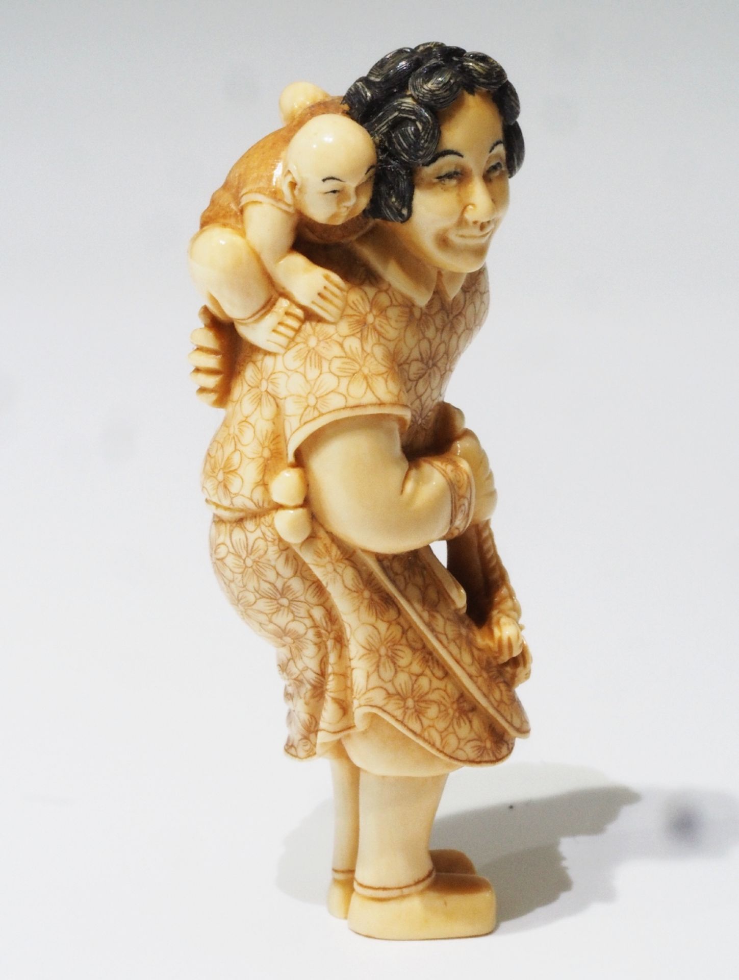 Netsuke, kleine Schnitzfigurengruppe, Japan. "Frau mit Posaune und Baby auf dem Rücken".