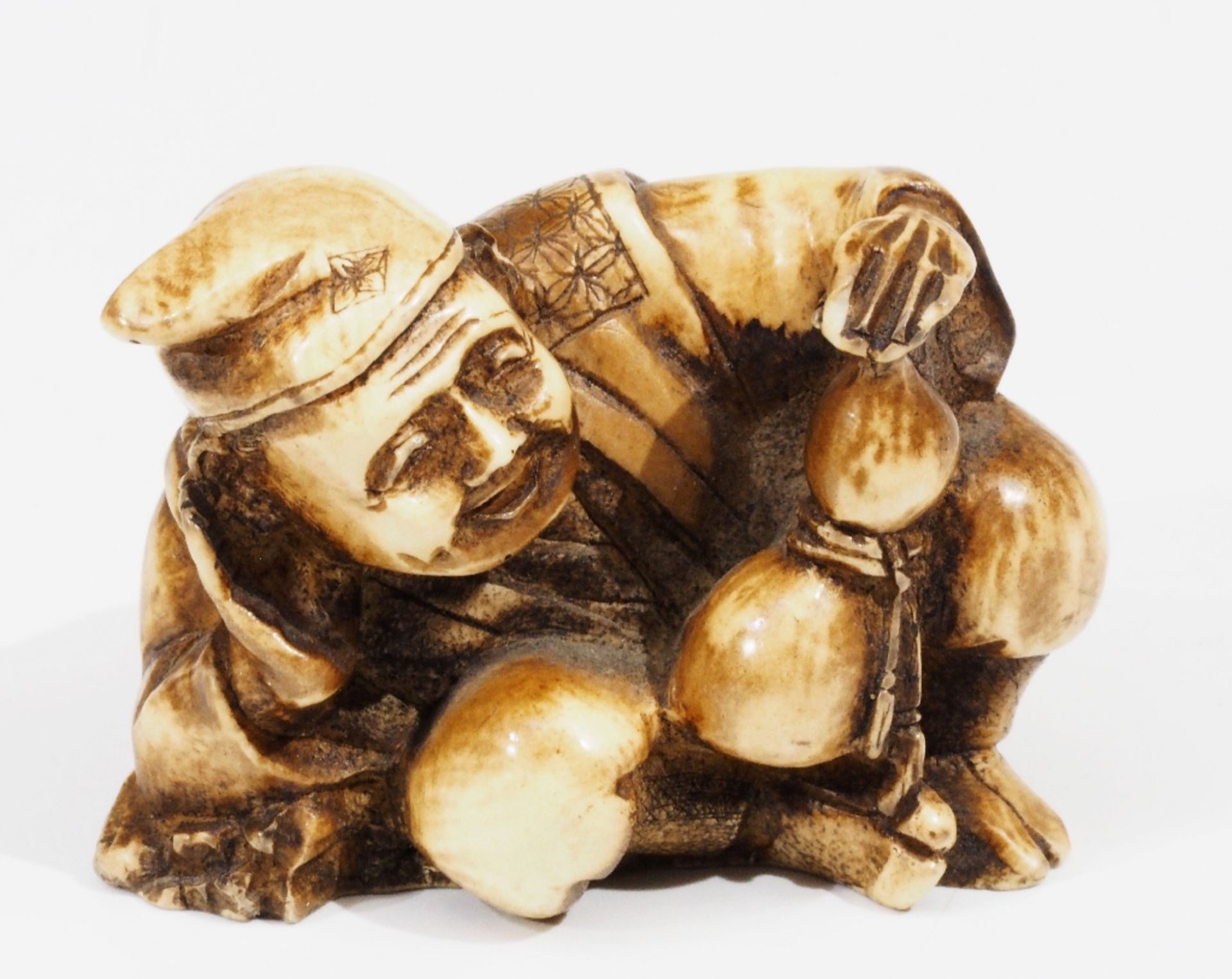 Netsuke, kleine Schnitzfigur, 20. Jahrhundert. "Ruhender Asiate" .