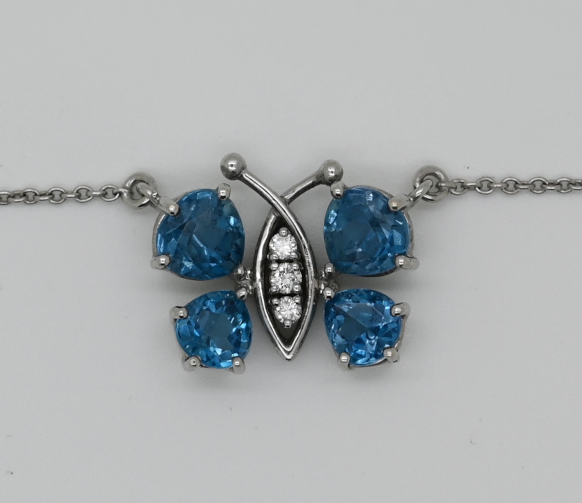 1 Collier WG 18ct., mit blauen und weißen Steinen, "Schmetterling", ca. 1,5 x 1,7cm, Tsp.