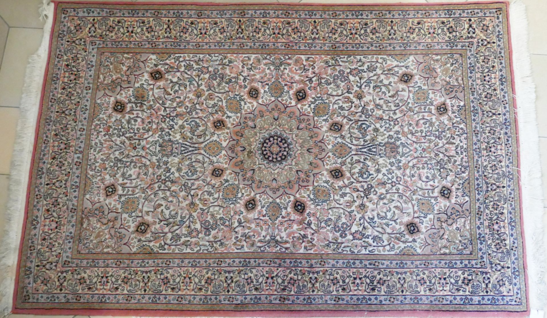 1 Teppich 20. Jh. beigefarbenes Mittelfeld mit rosafarbenem Blumendekor, ca. 182x125cm, Fransen, min