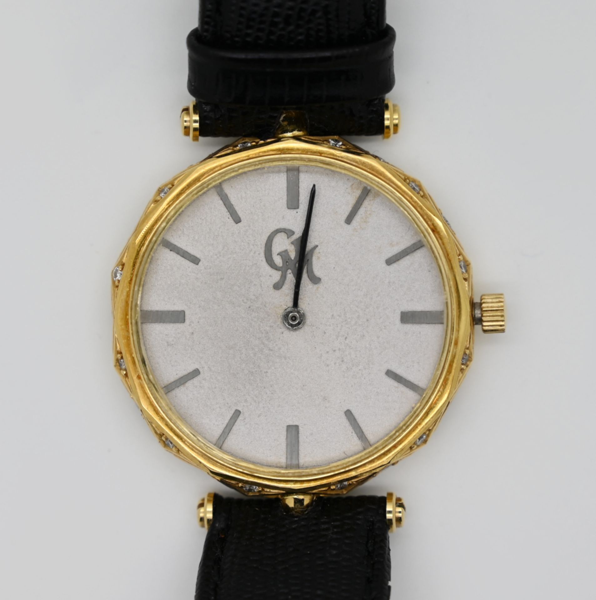 1 Armbanduhr GG 18ct., GM, mit kleinen Brillanten an der Seite, Durchmesser ca. 3,1cm, mit schwarzem