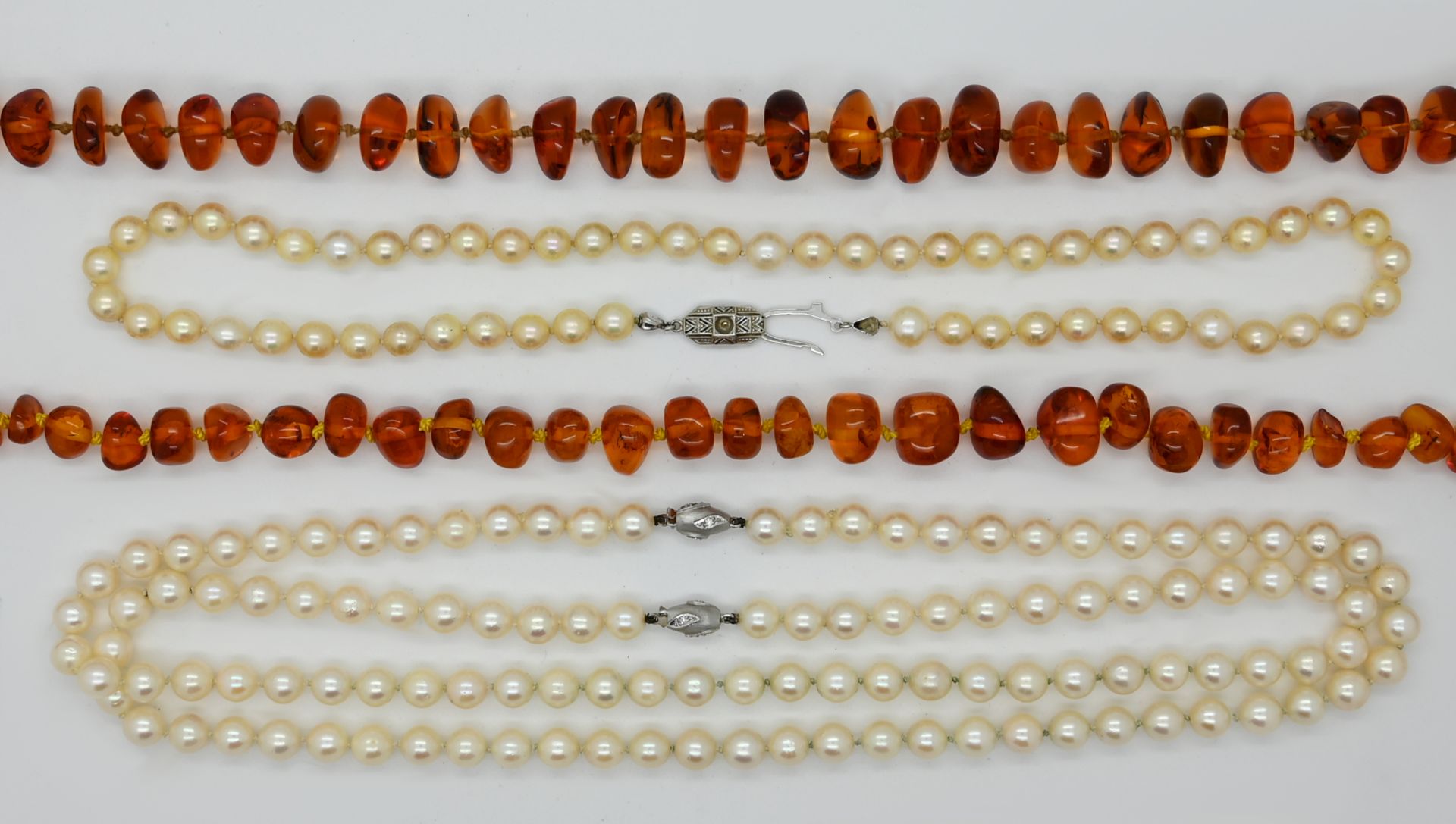 2 Perlenketten je mit gleichem Verschluss WG 14ct. und kleinen Brillanten, D ca. 0,7cm, 1 Perlenkett
