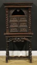 A 19th century Continental oak collector’s cabinet on stand, dentil cornice above an arched niche