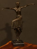 An Art Deco style dark patinated bronze, dancing girl in flapper dress and cap, arms outstretched,