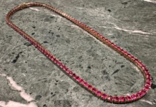 A 14ct gold and ruby tennis necklace, with one hundred and six cushion cut claw set stones, each