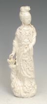 A Chinese blanc de chine figure, Guanyin, she stands, holding a basket, 26cm high, 18th century