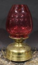 A late 19th century brass heater lamp, coin dot cranberry glass shade, 45.5cm high