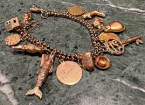 A gold coloured metal charm bracelet, with 16 charms including an articulated fish, church, key etc,