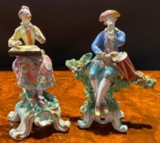 A pair of Bow figures, of musicians, she seated on tree stump wearing yellow jacket and floral dress