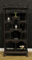 A Chinese hardwood open porcelain vitrine, shaped cresting pierced and carved with scrolling leaves,