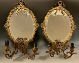 A near pair of Louis XVI Revival brass girandoles, each with an oval mirror plate and ribbon-tied