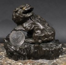 A Chinese brown patinated bronze censer and cover, cast as a temple lion, his paw resting on a glass