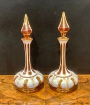 A pair of 19th century Bohemian cased milk and cranberry glass scent bottles, elongated faceted