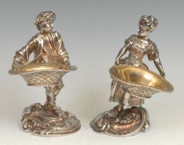 A pair of Rococo Revival silver plated figural salts, cast as a fisher boy and girl holding baskets,