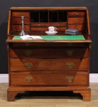 A George III mahogany bureau, fall front enclosing small drawers and pigeonholes, above four long