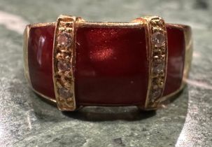 A French diamond and ruby red chatoyant enamel dress ring, with three ruby red sections divided by