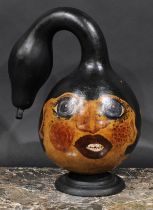 A folk art gourd, painted with stylised faces, 35cm high