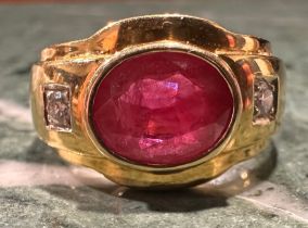 A ruby and diamond ring, central oval rub over set ruby approx 2.80ct, between round brilliant cut