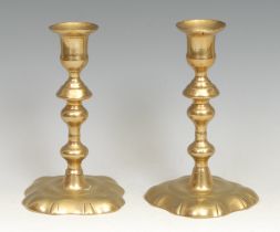 A pair of George II brass candlesticks, of seamed construction, knopped pillars, fluted square