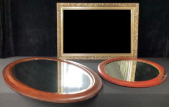 An Edwardian mahogany inlaid oval bevelled glass mirror; a Chinese red lacquered oval bevelled glass