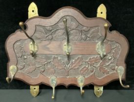 An oak Arts and Crafts shield shaped hall rack, carved with spreading leafy oak and acorn motifs,