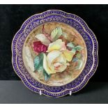 A Wedgwood shaped circular plate, painted by T. Dean, signed, with yellow and red roses, on mossy