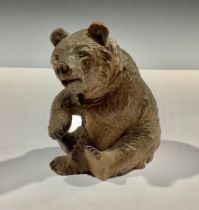 A Black Forest carved bear, seated with paw raised, 12cm