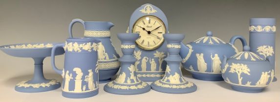 A Wedgwood Jasperware arched mantel clock, 19.5cm; a pair of candlesticks, 12cm; a teapot, sucrier