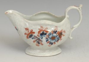A Liverpool cream boat, decorated in underglaze blue and overglaze red with flowers, picked out in